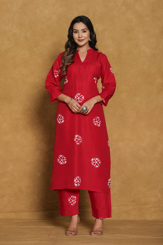Woman wearing a red traditional outfit with white patterns against a brown background