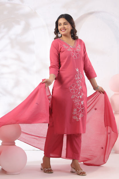 Woman wearing a pink traditional outfit with floral embroidery on a white background