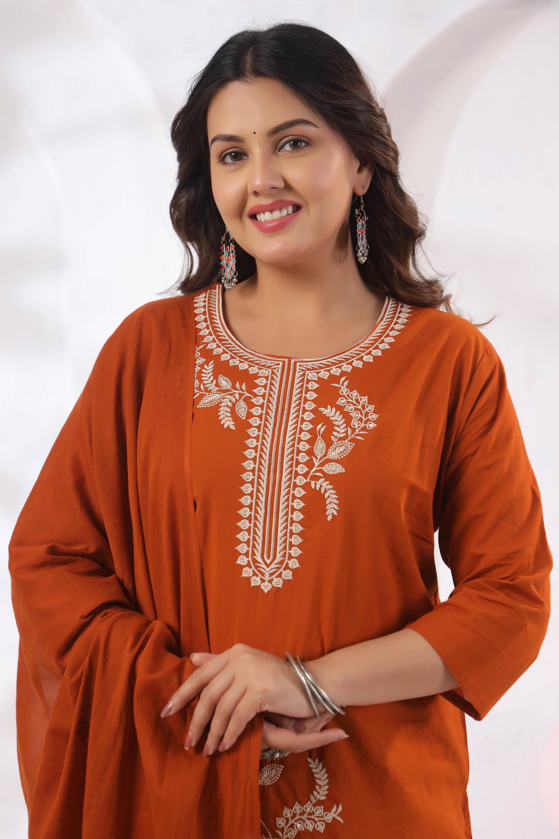 Woman wearing an orange kurta with white embroidery on a white background
