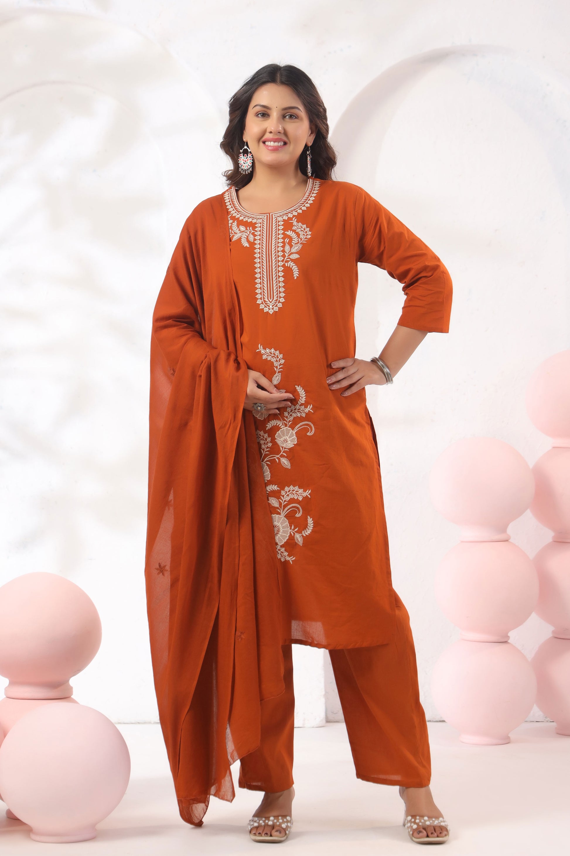 Woman wearing an orange traditional outfit with white embroidery against a white background